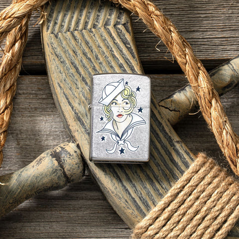 Lifestyle image of Sailor Girl Tattoo Design Street Chrome™ Windproof Lighter laying on a ships helm with rope around it.