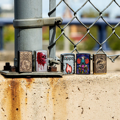 Lifestyle image of Zippo Flame Design Street Chrome™ Windproof Lighter standing with four other lighters in front of a chain link fence